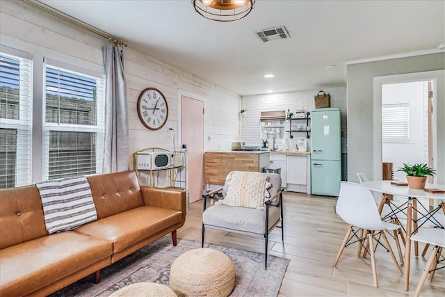 living room with brick wall and light hardwood / wood-style flooring