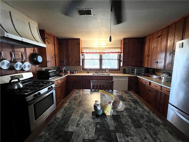 kitchen with visible vents, appliances with stainless steel finishes, brown cabinetry, and a sink