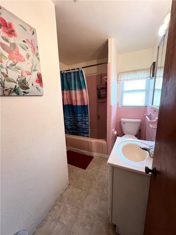 bathroom featuring tile patterned flooring, toilet, tile walls, vanity, and shower / tub combo with curtain