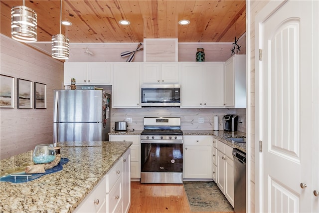 kitchen with light hardwood / wood-style floors, appliances with stainless steel finishes, light stone countertops, decorative light fixtures, and white cabinets