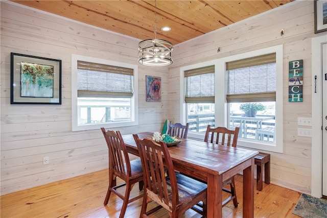 dining room featuring a notable chandelier, light hardwood / wood-style floors, wood walls, and wood ceiling