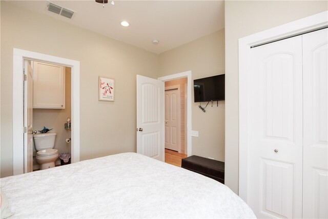 bedroom with a closet, hardwood / wood-style floors, and ensuite bath