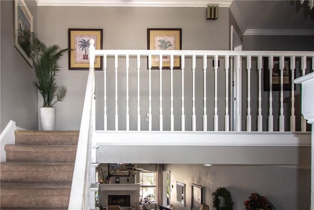 stairway featuring a fireplace and crown molding