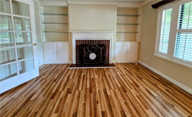 515 Deforrest St, Corpus Christi, TX 78404 - unfurnished living room featuring wood finished floors, built in shelves, ornamental molding, plenty of natural light, and a fireplace