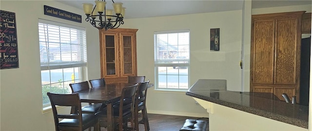 dining space with plenty of natural light, dark wood-type flooring, and a notable chandelier