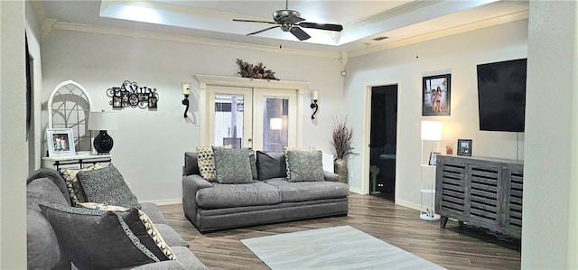 living room with a raised ceiling, crown molding, dark wood-type flooring, and french doors