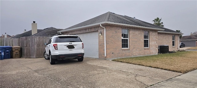 view of side of property with central AC, a yard, and a garage