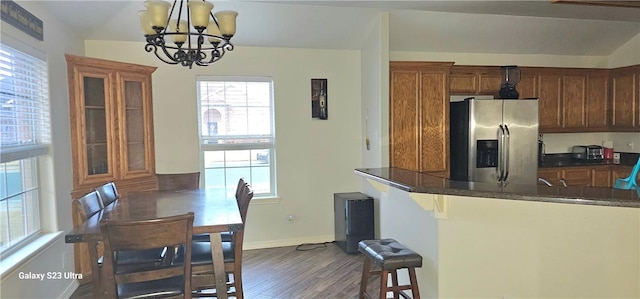 kitchen featuring a kitchen bar, decorative light fixtures, stainless steel fridge with ice dispenser, dark hardwood / wood-style flooring, and a notable chandelier