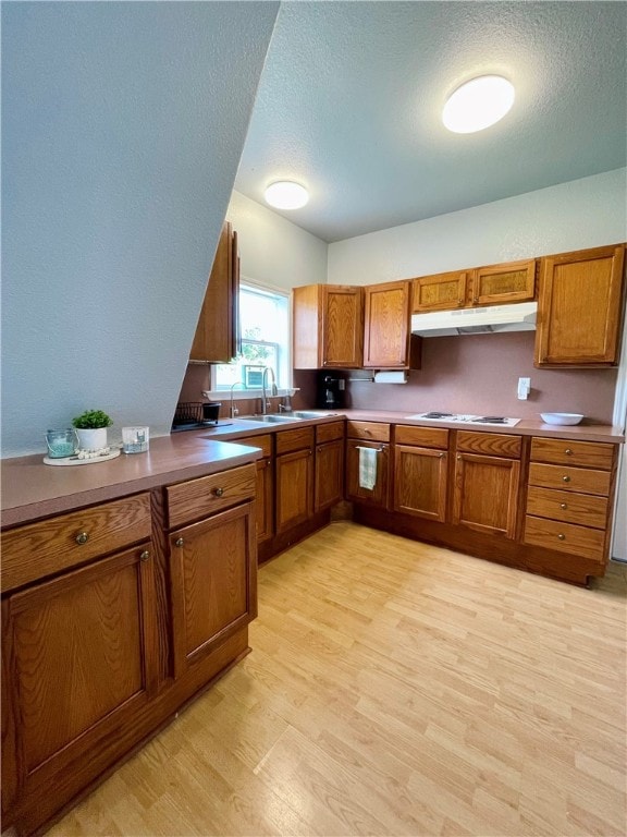 343 Bracht, Rockport, TX 78382 - kitchen featuring under cabinet range hood, brown cabinetry, light wood finished floors, white gas cooktop, and a textured ceiling