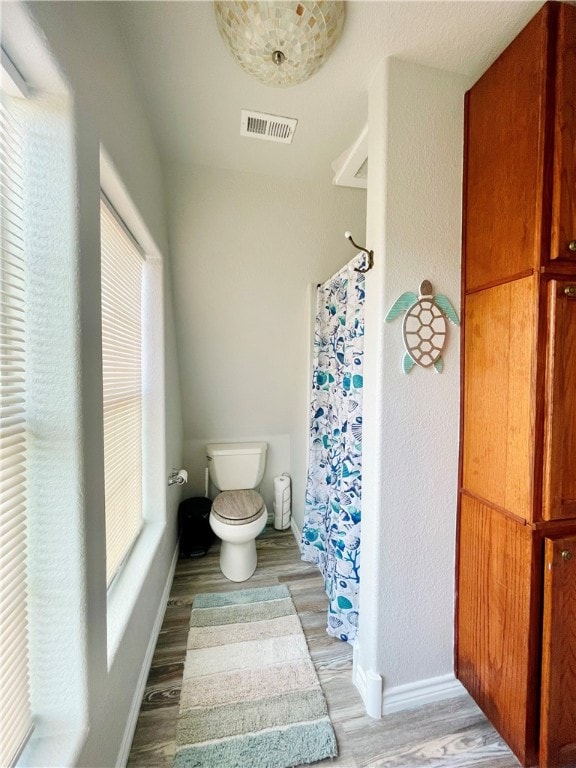 bathroom featuring a healthy amount of sunlight, hardwood / wood-style flooring, and toilet