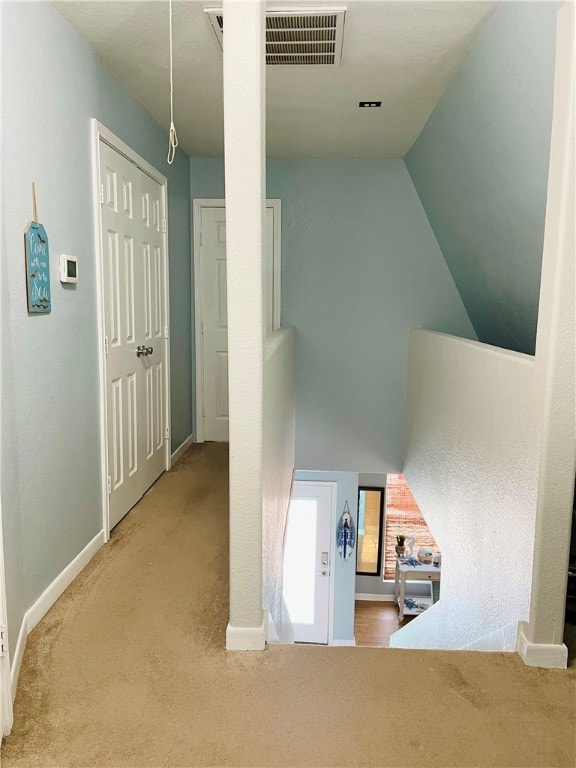 hallway with vaulted ceiling and carpet floors