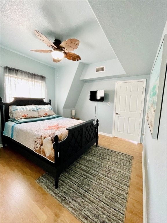 bedroom with a textured ceiling, hardwood / wood-style flooring, and ceiling fan