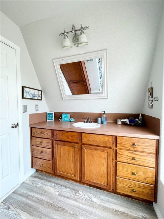 bathroom featuring hardwood / wood-style floors, lofted ceiling, and vanity