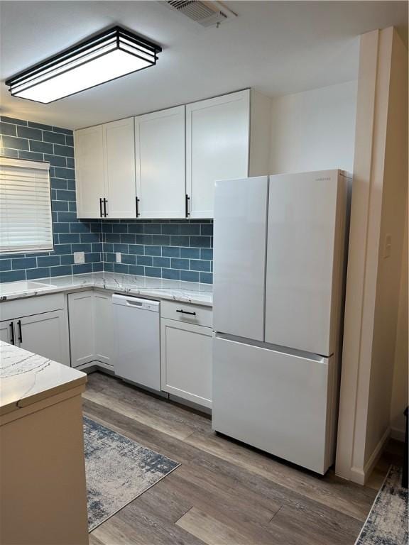 kitchen with visible vents, decorative backsplash, wood finished floors, white cabinets, and white appliances