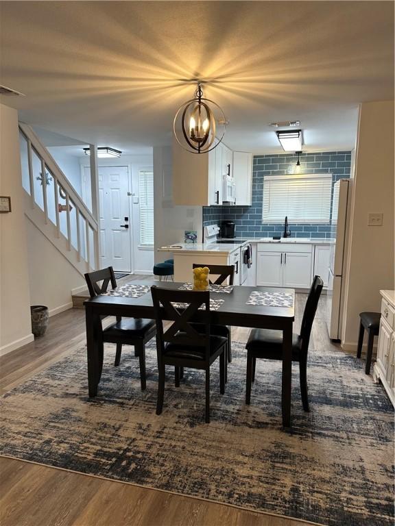 dining room featuring stairway, wood finished floors, visible vents, and baseboards