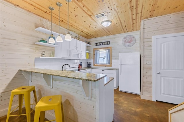 kitchen with white appliances, kitchen peninsula, white cabinets, and a breakfast bar