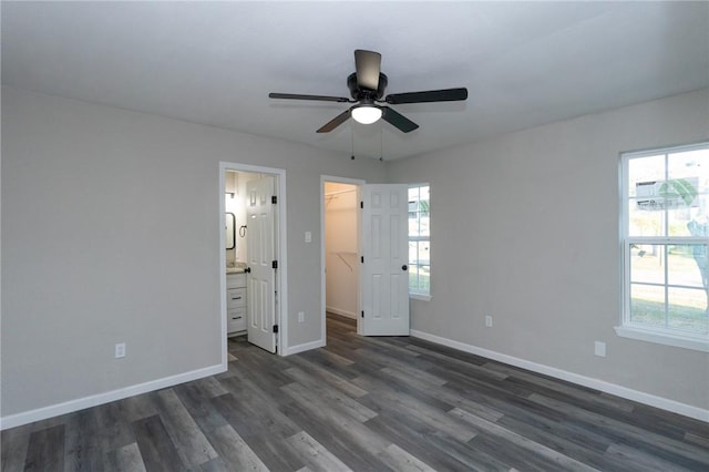 unfurnished bedroom featuring dark wood-type flooring, ensuite bathroom, ceiling fan, a spacious closet, and a closet