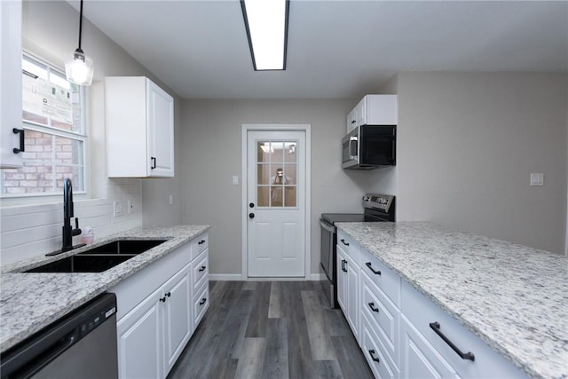 kitchen with decorative light fixtures, stainless steel appliances, white cabinetry, and sink