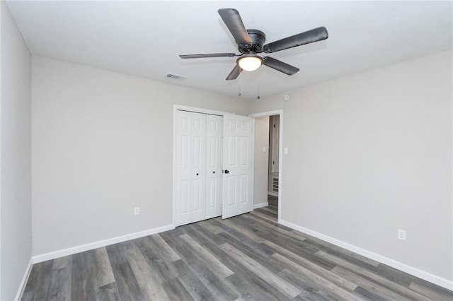 unfurnished bedroom with ceiling fan, dark wood-type flooring, and a closet