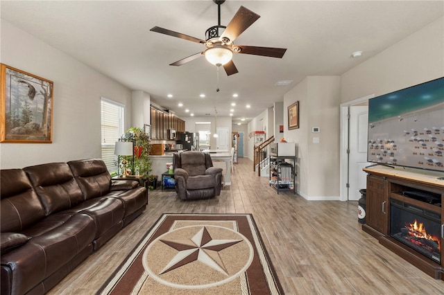 10343 Rosalina Loop, Converse, TX 78109 - living area with light wood-style floors, a ceiling fan, stairway, and a glass covered fireplace