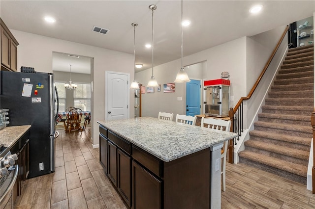 10343 Rosalina Loop, Converse, TX 78109 - kitchen with stainless steel appliances, dark brown cabinets, light wood-type flooring, a kitchen island, and a chandelier