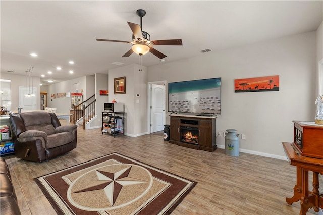 10343 Rosalina Loop, Converse, TX 78109 - living area with wood finished floors, stairway, a ceiling fan, recessed lighting, and a warm lit fireplace