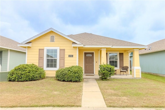bungalow-style house with a front lawn, covered porch, and roof with shingles