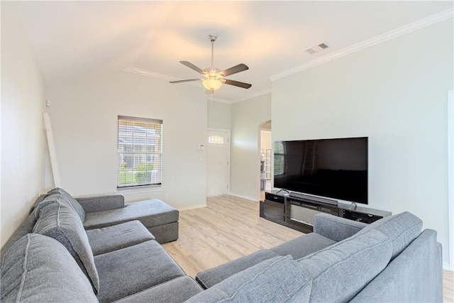 living area featuring light wood-type flooring, a ceiling fan, arched walkways, baseboards, and crown molding