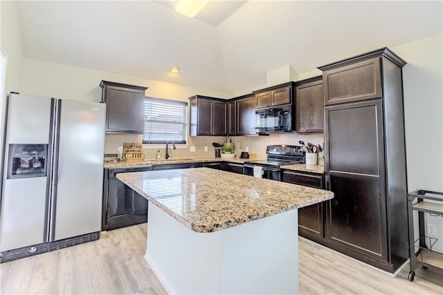 kitchen featuring black appliances, a sink, dark brown cabinets, light wood-type flooring, and a center island