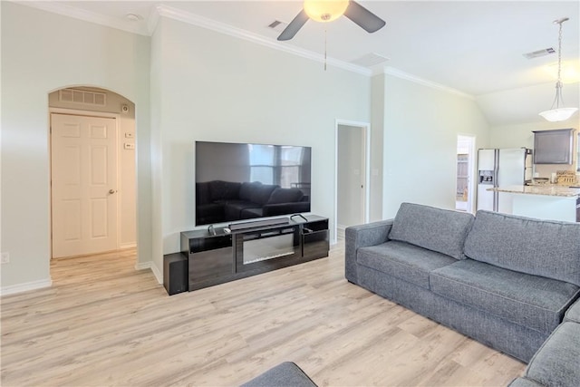 living area with light wood-style floors, ceiling fan, crown molding, baseboards, and arched walkways