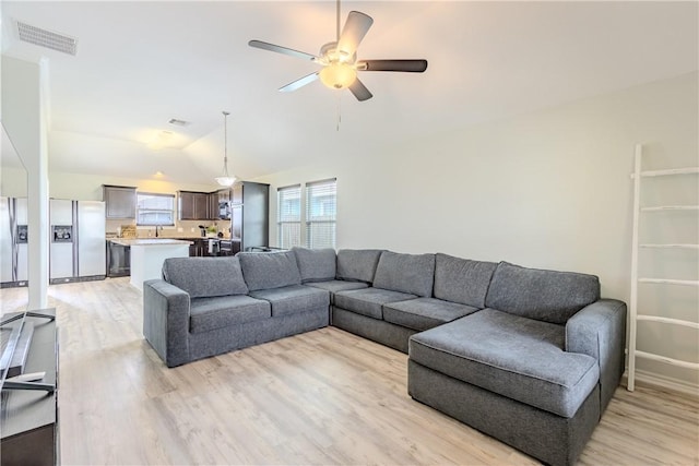 living area with light wood-type flooring, lofted ceiling, and a ceiling fan