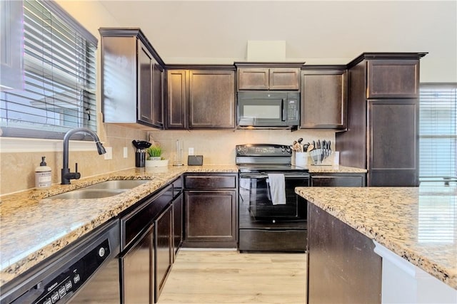 kitchen featuring black appliances, a sink, light wood-style flooring, and dark brown cabinetry