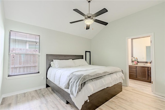 bedroom featuring light wood-style floors, lofted ceiling, baseboards, ceiling fan, and ensuite bath