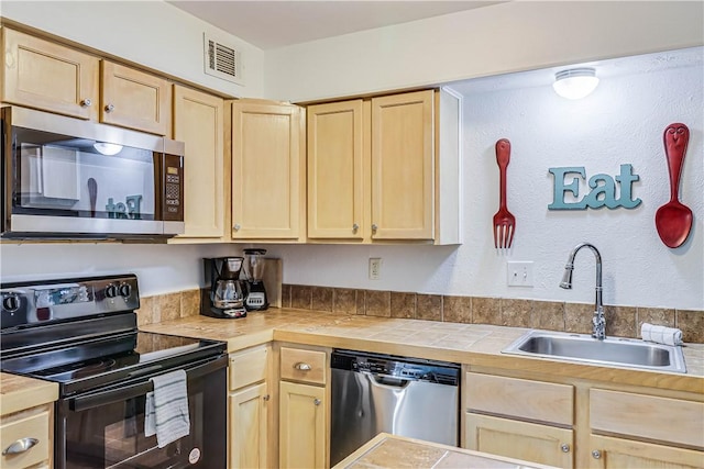 kitchen with visible vents, appliances with stainless steel finishes, a sink, and light brown cabinetry