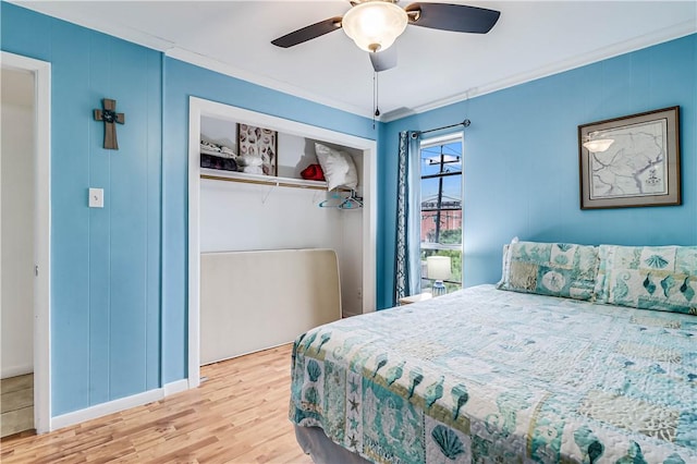 bedroom with ceiling fan, ornamental molding, a closet, and wood finished floors