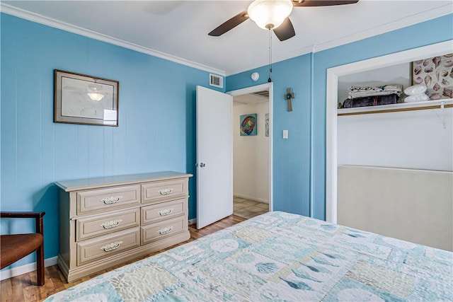 bedroom featuring visible vents, a ceiling fan, wood finished floors, crown molding, and a closet