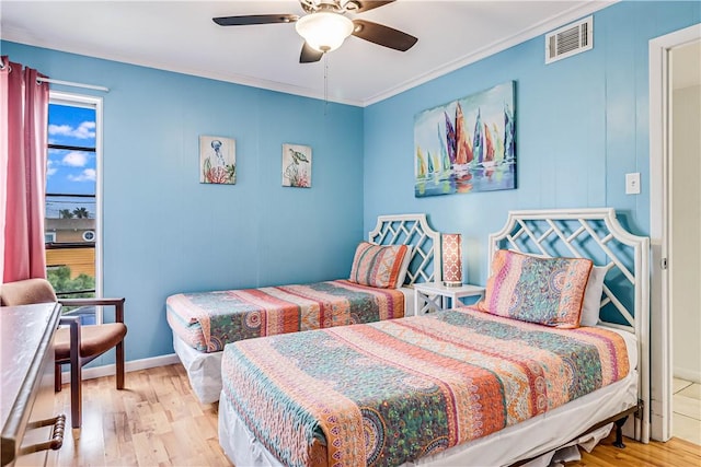 bedroom with ornamental molding, wood finished floors, visible vents, and baseboards