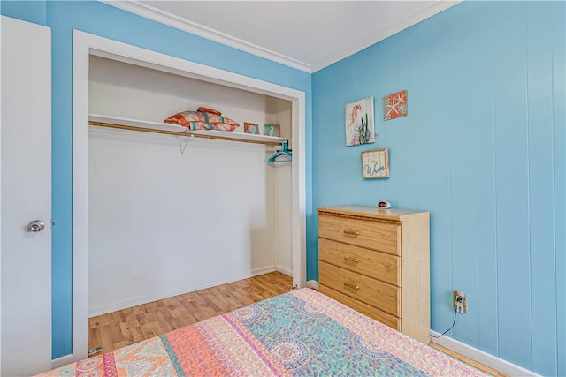 bedroom with a closet, ornamental molding, and wood finished floors