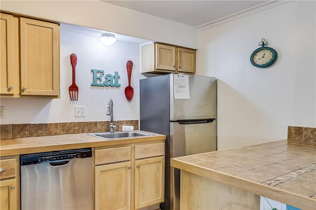 kitchen featuring tile countertops, a peninsula, stainless steel appliances, light brown cabinets, and a sink