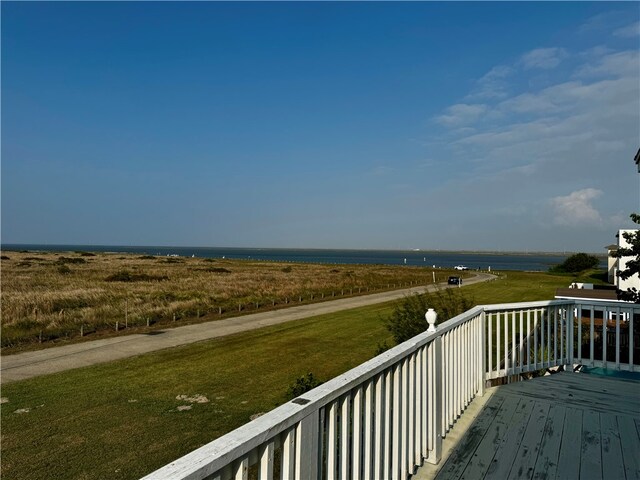 wooden terrace with a water view and a lawn