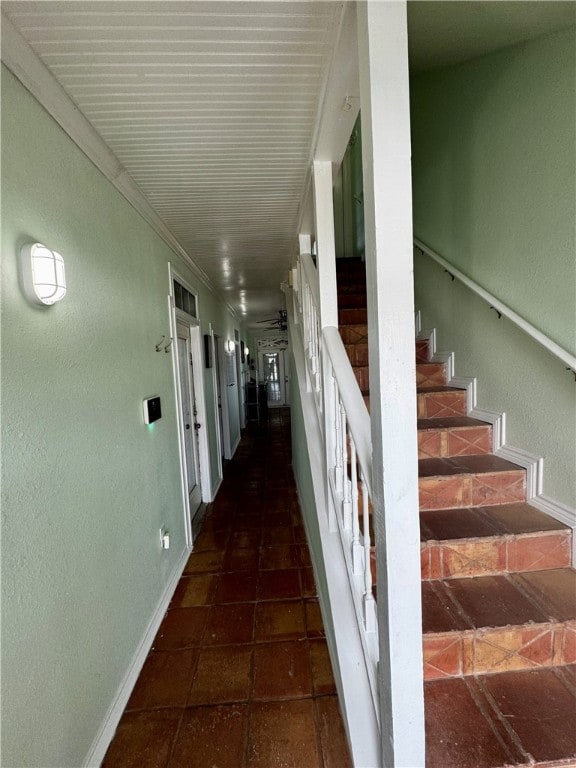 hallway with dark tile patterned flooring and ornamental molding