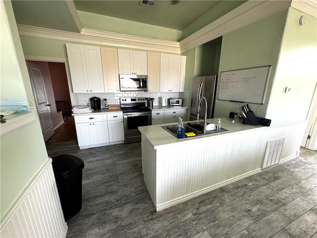 kitchen featuring ornamental molding, stainless steel appliances, backsplash, sink, and white cabinets