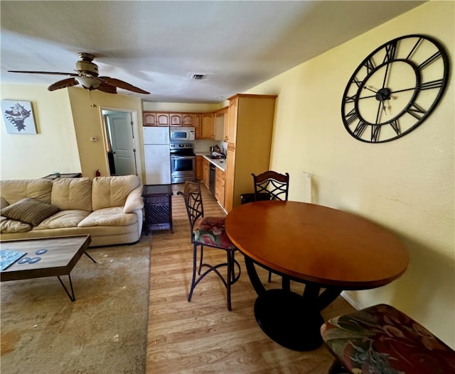 dining space with ceiling fan and light hardwood / wood-style flooring