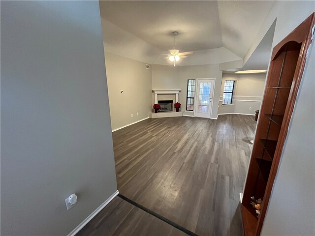 unfurnished living room with ceiling fan, lofted ceiling, and dark wood-type flooring