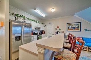 kitchen with a center island, appliances with stainless steel finishes, crown molding, and white cabinets