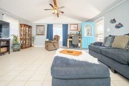 living area featuring vaulted ceiling with beams and light tile patterned floors