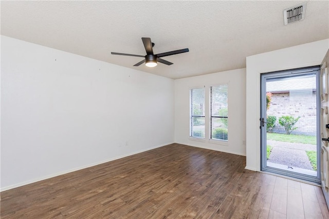 unfurnished room with a textured ceiling, ceiling fan, visible vents, baseboards, and wood finished floors