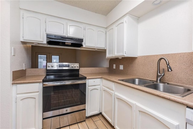 kitchen with a sink, ventilation hood, stainless steel electric range oven, and white cabinets