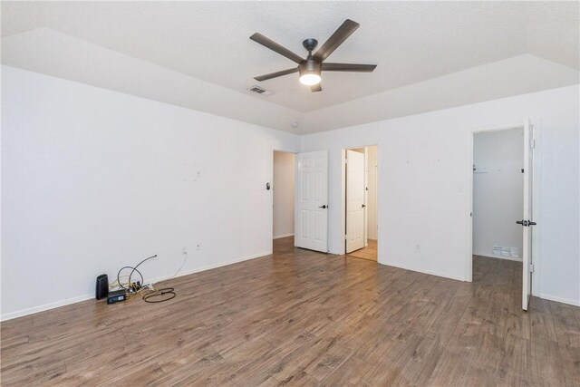 unfurnished bedroom with wood finished floors, baseboards, visible vents, and a walk in closet