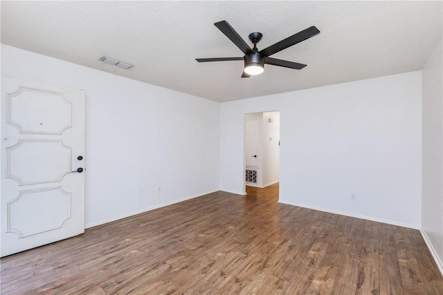 empty room featuring baseboards, visible vents, wood finished floors, and a ceiling fan